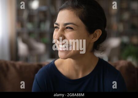 Lächelnde indische Frau schaut in der Ferne und träumt lachend Stockfoto