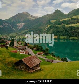 Schweizer Dorf Lungern mit seinen traditionellen Häusern und alten Kirchturm Alter Kirchturm entlang der wunderschönen smaragdgrünen See Firma Lungerersee, Kanton Obwalden Stockfoto