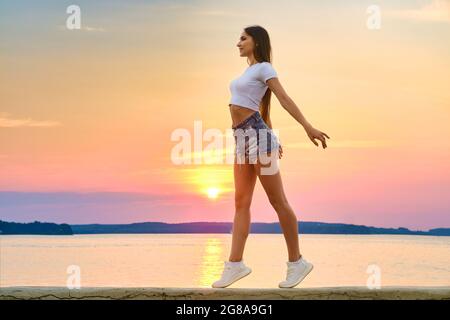 Glückliche und ungestüme junge Frau genießt Freiheit in der Sonnenuntergangszeit Stockfoto