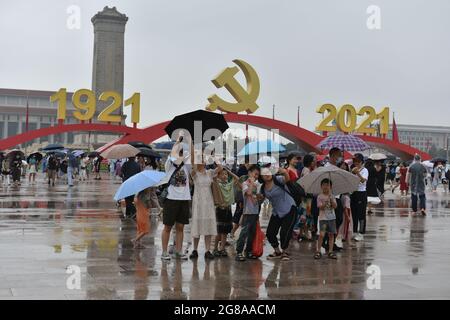 Peking, China. Juli 2021. Touristen fotografieren unter dem Parteiemblem der Kommunistischen Partei Chinas während eines Besuchs auf dem Platz des Himmlischen Friedens an einem regnerischen Tag.das meteorologische Observatorium von Peking verbesserte sein oranges Regensturmwarnsignal, Schnitt vorübergehend mehrere Straßen ab, schloss einige Züge ab und stornierte einige Flüge. (Foto von Sheldon Cooper/SOPA Images/Sipa USA) Quelle: SIPA USA/Alamy Live News Stockfoto