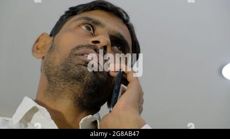 Ein Porträt eines indischen Mannes, der auf einem Smartphone spricht Stockfoto