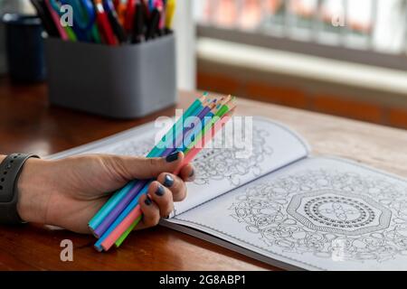 Buch Mandalas zum Ausmalen und eine Hand mit Buntstiften Stockfoto