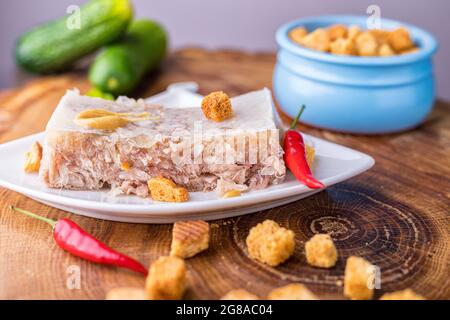 Fleisch mit Rind- und Schweinefleisch auf einer weißen Untertasse. Kalte Vorspeise mit Zwieback und Gurke. Nahaufnahme. Stockfoto