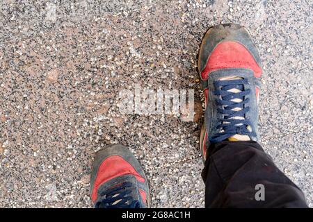 Beschädigte Personenschuhe auf gesalzenem Bürgersteig in der Stadt während der Wintersaison Stockfoto