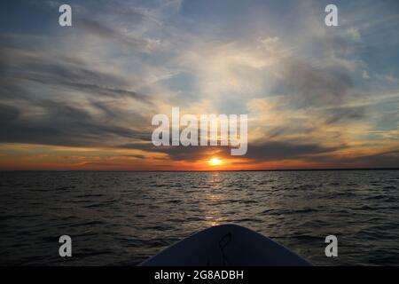 Abend auf dem Meer untergehende Sonne auf dem Kurs des Bootes, dramatische bewölkte Landschaft Stockfoto