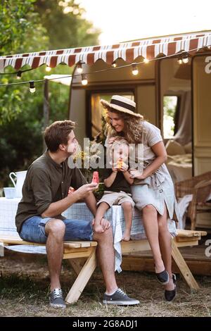 Junge Eltern genießen Urlaub sitzen im rv van Haus im Freien, reisen mit kleinen Sohn im Wohnwagen Anhänger Stockfoto