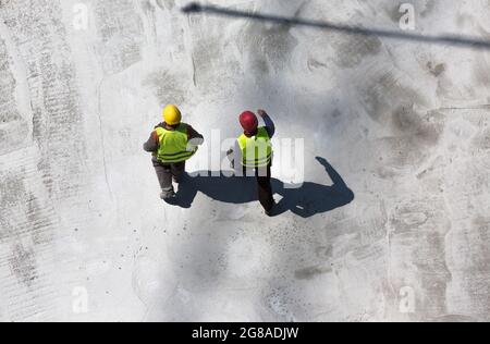 Luftaufnahme von zwei Arbeitern, die über die Baustelle laufen Stockfoto