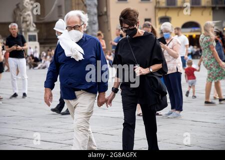 Älteres elegantes Paar, Touristen, die auf der Straße spazieren, mit Gesichtsmasken während der Quarantäne 19 in Italien. Langsame Wiedereröffnung nach der Pangemik von Florenz Stockfoto