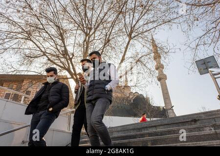 Eminonu, Istanbul, Türkei - 03.05.2021: Menschen, die vor der Istanbuler Moschee die Treppe hinuntergehen, und Bäume von der Stadttreppe aus, aus der unteren Sicht Stockfoto