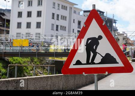 Straßenbauschild für den Wiederaufbau einer Brücke in Einsiedeln, Schweiz. Im Hintergrund befindet sich eine provisorische Brücke für Fußgänger. Stockfoto