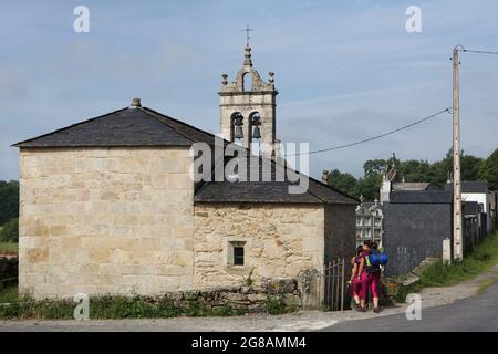 Camino de Santiago (Jakobsweg). Pilger besuchen die Kirche Santa María de Ferreiros (Iglesia de Santa María de Ferreiros) in Mirallos in Galizien, Spanien. Die französische Route des Camino de Santiago führt durch diese Siedlung auf dem Weg von Barbadelo nach Portomarín. Stockfoto