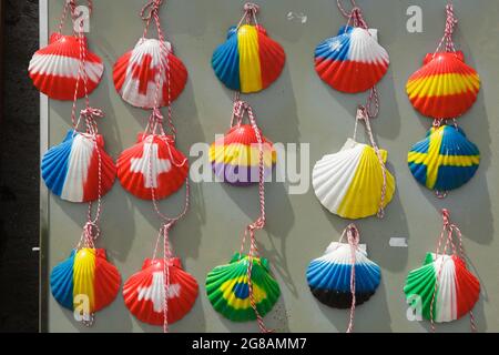 Camino de Santiago (Jakobsweg). Muschelschalen mit verschiedenen Nationalflaggen, die in einem Souvenirladen in der Nähe des Dorfes A Tellada in Galicien, Spanien, verkauft werden. Die französische Route des Camino de Santiago führt durch dieses Dorf auf dem Weg von Barbadelo nach Portomarín. Die Jakobsmuschel, auch bekannt als die Jakobsmuschel, ist ein traditionelles Symbol der Wallfahrt nach Santiago de Compostela. Stockfoto