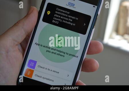 Yeovil, Somerset, England, Juli 18 2021: Smartphone mit NHS Test und Trace App geöffnet, zeigt, dass Coronavirus-Einschränkungen bestehen bleiben und die Option besteht Stockfoto