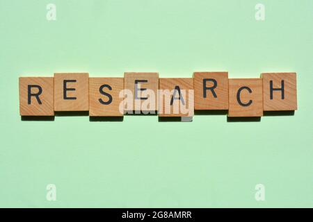 Forschung, Wort in Holzalphabet Buchstaben isoliert auf grünem Hintergrund