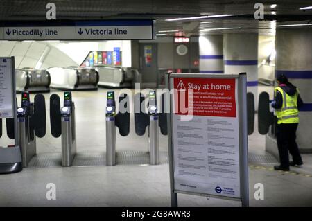 London, Großbritannien. März 2020. Ein Mitarbeiter ist im Bahnhof Kings Cross im Einsatz, auf Schilder, auf denen alle nicht wesentlichen Mitarbeiter informiert sind, dass sie während der vorgeschriebenen Restriktionen von 19 zu Hause bleiben sollen.nach mehr als einem Jahr Beschränkungen für das Tragen von Gesichtsmaske und die soziale Distanzierung der Reisenden werden am Montag, dem 19. Juli, beendet. Die Regierung hat immer noch das Tragen von Gesichtsmasken empfohlen und zusätzlichen Platz in überfüllten Räumen in Innenräumen ermöglicht. Kredit: SOPA Images Limited/Alamy Live Nachrichten Stockfoto