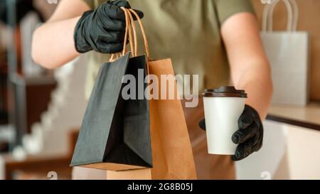 Der Kellner gab Essen zum Mitnehmen, während die Stadt um 19 Uhr geschlossen wurde, das Coronavirus wurde heruntergefahren. Unkenntlich Frau Kellner, weibliche Hände in Handschuhen arbeiten mit Take Away Stockfoto