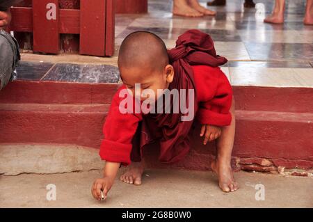 Burmesischer Anfänger, der Geld spielt, um Spenden von burma-Leuten und ausländischen Reisenden zu erhalten, besuchen Respect Praying am Shwezigon Pagoda Paya Tempel in Bagan Stockfoto