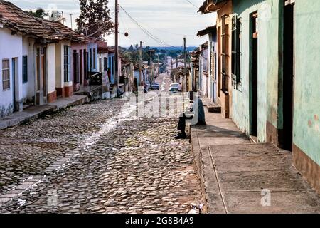 Mann, der auf einem Fußweg im Stadtzentrum von Trinidad, Sancti Spiritus, Kuba sitzt Stockfoto