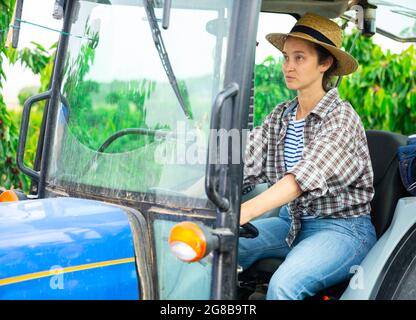 Mädchen mittleren Alters, die auf einem Traktor im Obstgarten arbeiten Stockfoto