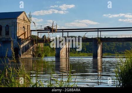 Ein verlassenes Wasserkraftwerk am Fluss. Blick vom Flussufer Stockfoto