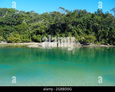 Schöner sonniger blauer Himmel im Winter, blaugrünes Meerwasser, das im Sonnenschein im Flutbach, Boambee Reserve an der NSW Mid North Coast, glitzert Stockfoto