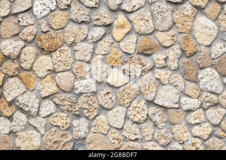 Steinmauer Hintergrund, beige Kopfsteinpflaster, abstrakte Gesteinsstruktur, mineralische Pflaster, helle Backsteintapete, Raues Mauerwerk. Grunge Boden, Felsbrocken Stockfoto