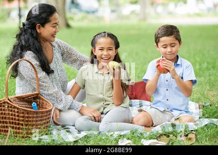 Asiatische Familie von drei sitzen auf dem Gras und Mittagessen während des Picknicks im Park Stockfoto