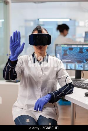 Laborarzt erlebt virtuelle Realität mit vr-Brille im medizinischen Forschungslabor. Team von Forschern arbeiten mit Geräten Gerät, Zukunft, Medizin, Gesundheitswesen, professionelle, Vision, Simulator. Stockfoto