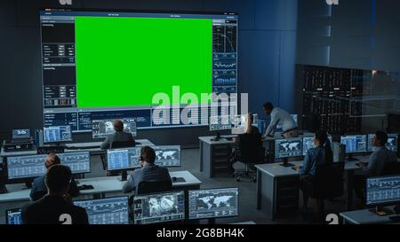 Großer grüner Bildschirm horizontaler Mock oben in einem Mission Control Center Raum mit Flight Director und anderen Controllern, die an Computern arbeiten. Team von Stockfoto