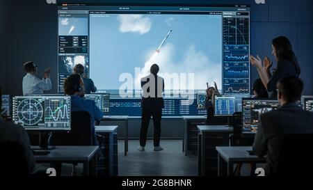 Eine Gruppe von Menschen im Mission Control Center wird Zeuge eines erfolgreichen Raketenstarts. Flight Director ist nervös vor dem Bildschirm und Stockfoto