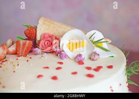 Nahaufnahme eines wunderschönen Geburtstagstortes mit Erdbeeren, Marmeladen, Waffelkegel und Mastixblumen auf dem Tisch. Stockfoto