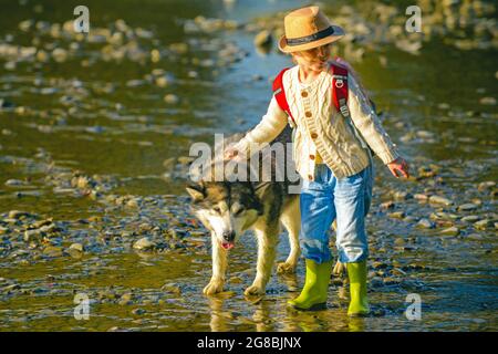 Kinder und Hunde erkunden. Nette Kinder mit Hund, die an einem sonnigen Sommertag im Fluss spazieren gehen. Kinder Touristen und Hund in schöner Natur. Stockfoto