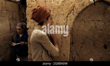 Ein religiöser Jude trauert am Eingang der Kleinen Westmauer, auch bekannt als HaKotel HaKatan oder das kleine Kotel, das eine jüdische religiöse Stätte im muslimischen Viertel ist, am jüdischen Fest der Tisha B'AV am 18. Juli 2021 in Jerusalem, Israel. In der Nacht des 17. Juli versammelten sich Juden auf der ganzen Welt, um aus dem Buch der Klagelieder zu lesen und damit den Beginn des Tisha B'AV, des jährlichen Fastentages zum Gedenken an die Zerstörung des ersten und zweiten Tempels in Jerusalem, zu begehen. Stockfoto