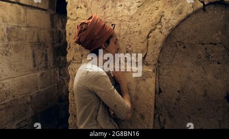 Ein religiöser Jude trauert am Eingang der Kleinen Westmauer, auch bekannt als HaKotel HaKatan oder das kleine Kotel, das eine jüdische religiöse Stätte im muslimischen Viertel ist, am jüdischen Fest der Tisha B'AV am 18. Juli 2021 in Jerusalem, Israel. In der Nacht des 17. Juli versammelten sich Juden auf der ganzen Welt, um aus dem Buch der Klagelieder zu lesen und damit den Beginn des Tisha B'AV, des jährlichen Fastentages zum Gedenken an die Zerstörung des ersten und zweiten Tempels in Jerusalem, zu begehen. Stockfoto