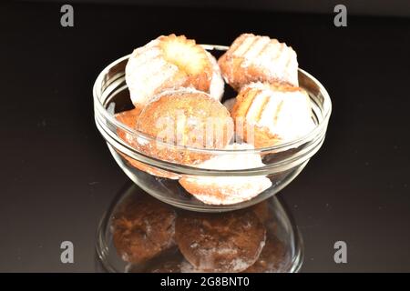 Mehrere hausgemachte leckere Muffins in einer Glasplatte, Nahaufnahme, auf schwarzem Hintergrund. Stockfoto