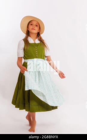 Tanzendes Mädchen im Dirndl mit Hut, der die Schürze in einer Hand hält und sich dreht. Stockfoto