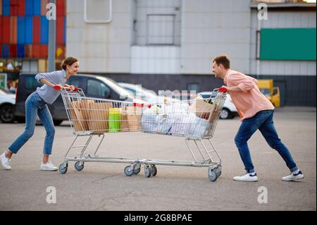 Paar mit Taschen in Karren Witze auf Parkplatz Stockfoto