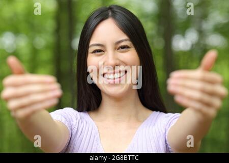 Vorderansicht Porträt einer glücklichen asiatischen Frau winkend kommen Sie hier lädt Sie in einen Park Stockfoto