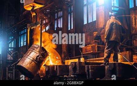 Flüssiges Metall, das in Formen fließt. Metallschmelzen in Öfen in Gießerei metallurgischen Werk, Schwerindustrie. Stockfoto