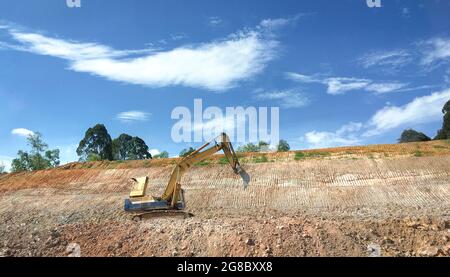 Bagger an einem Hang, beteiligt an Erdbauprojekten oder Straßenarbeiten. Stockfoto