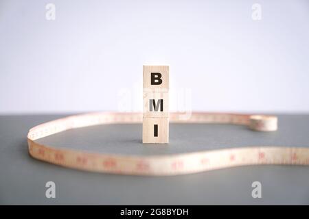 BMI-Wort auf Holzwürfeln mit Maßband auf dem Tisch. Speicherplatz kopieren. Stockfoto