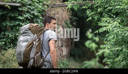 Ein Mann auf einer Wanderung mit einem großen Rucksack reist durch den Wald. Stockfoto