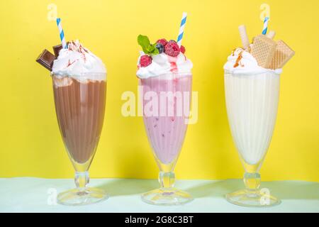 Sommerliche Erfrischungsgetränke, Milchshakes, verrückte Shakes mit Eis, Beeren, Vanille, Schokolade. Auf einem hellblau-gelben Hintergrund Stockfoto
