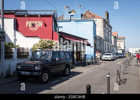 Ein Mann reinigt die Straße an der Loire, gesäumt von bunten Restaurants und Cafés im alten Fischerdorf Trentemoult, Frankreich. Stockfoto