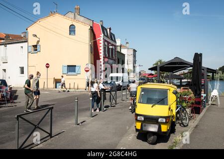 Die Menschen gehen entlang der Straße an der Loire vorbei an bunten Restaurants und Cafés im alten Fischerdorf Trentemoult, Frankreich. Stockfoto