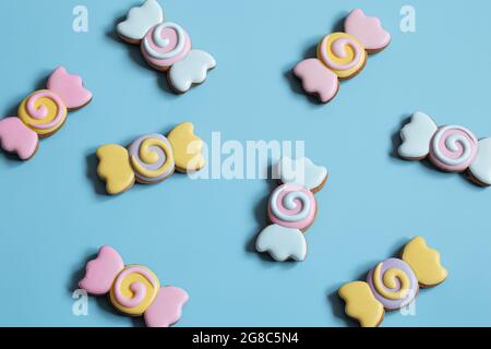 Bunte festliche Lebkuchen in Form von Bonbons mit Glasur auf blauem Hintergrund bedeckt. Stockfoto