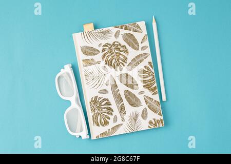 Weißer Notizblock Brille Bleistift auf blauem Hintergrund. Stockfoto
