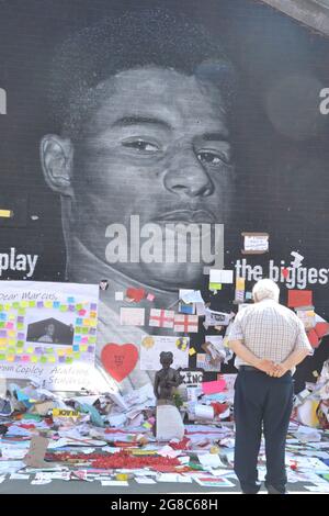 Manchester, Vereinigtes Königreich, 19. Juli 2021 der Stadtrat von Manchester wird dafür sorgen, dass am Marcus Rashford Wandgemälde in der Moorfield Street, Withington, Manchester, England, Vereinigtes Königreich, erhalten bleiben. Mitarbeiter der Gallerien-Abteilung des Rates halten die Ehrungen aufrecht. Auf dem riesigen MBE-Wandgemälde des Manchester United-Spielers Marcus Rashford, das nach dem Fußballverlust der Euro2020 am 11. Juli 2021 durch missbräuchliche Graffiti verwüstet wurde, haben Menschen Tausende unterstützende Notizen, Bilder, Fahnen, Blumen und antirassistische Botschaften hinterlassen. Quelle: Terry Waller/Alamy Live News Stockfoto