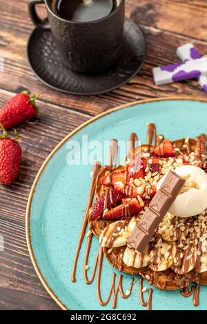 Herzwaffel mit Banane und Erdbeere mit Gummy Candy und Eis darauf. Stockfoto