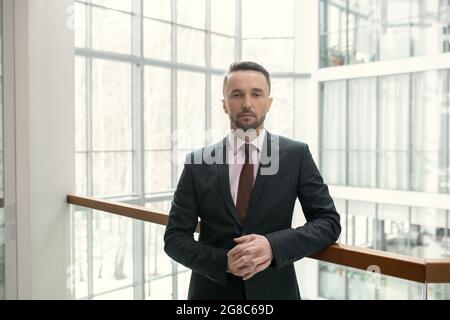 Porträt eines selbstbewussten Geschäftsmannes in elegantem Anzug, der in der Bürohalle steht Stockfoto